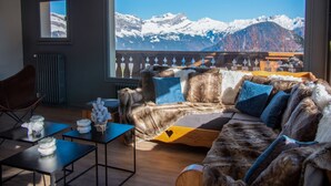 A cozy room with a fur-covered sofa, a wooden coffee table, and a view of snow-capped mountains. - Hôtel Arbois Bettex (Saint-Gervais-les-Bains)