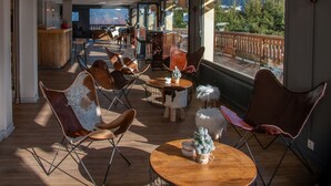 A spacious indoor area with leather chairs and tables, large windows offering a view of the outdoors. - Hôtel Arbois Bettex (Saint-Gervais-les-Bains)
