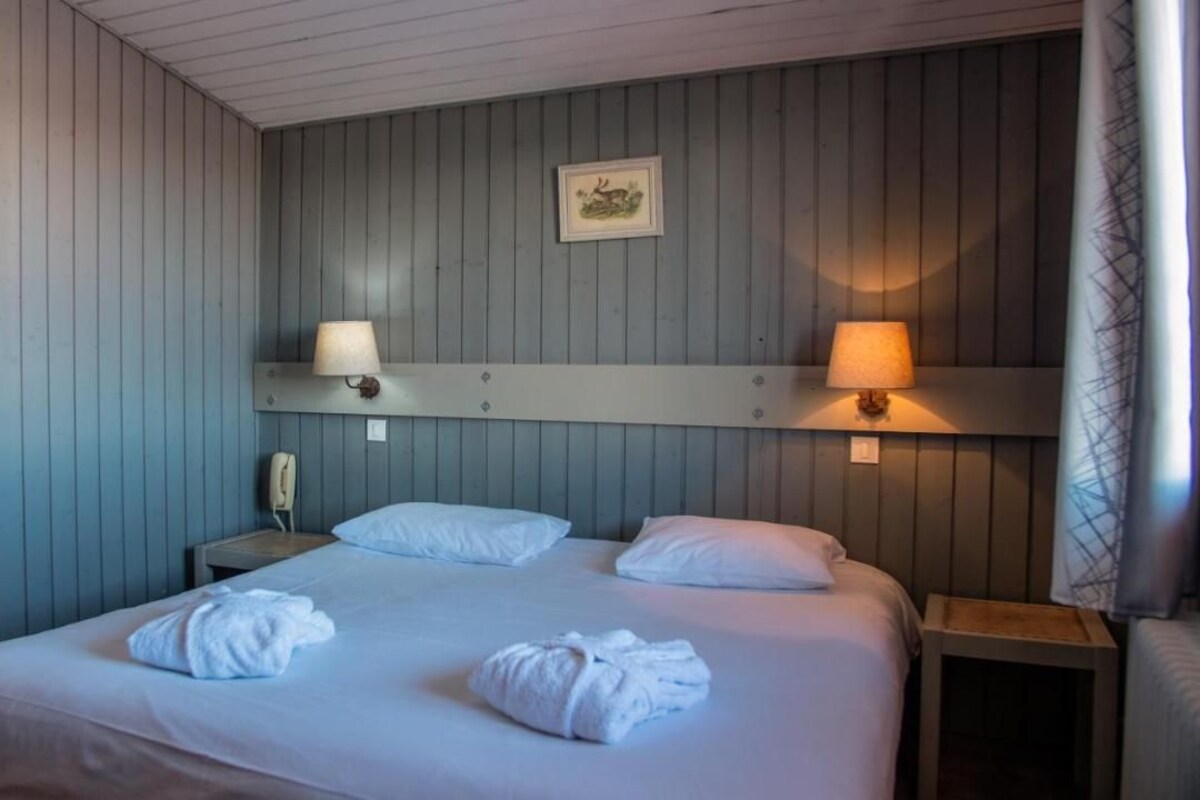 A hotel room with a large bed, two bedside lamps, a nightstand, and a framed picture on the wall.