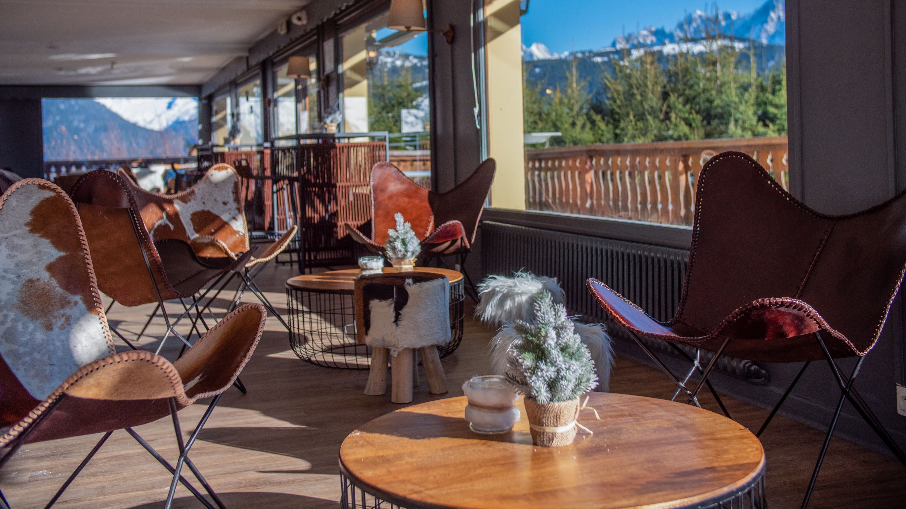 Cómoda zona de estar al aire libre con sillones de cuero y mesas, con vistas a un paisaje montañoso.