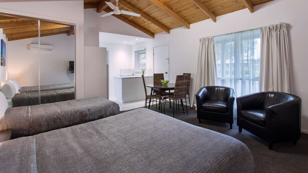 A room with two beds, a dining table with chairs, a ceiling fan, and large windows with curtains. - Best Western Colonial Village Motel (Warrnambool)