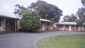 A building with a brick exterior, a covered porch, and a large tree in front. - Best Western Colonial Village Motel (Warrnambool)