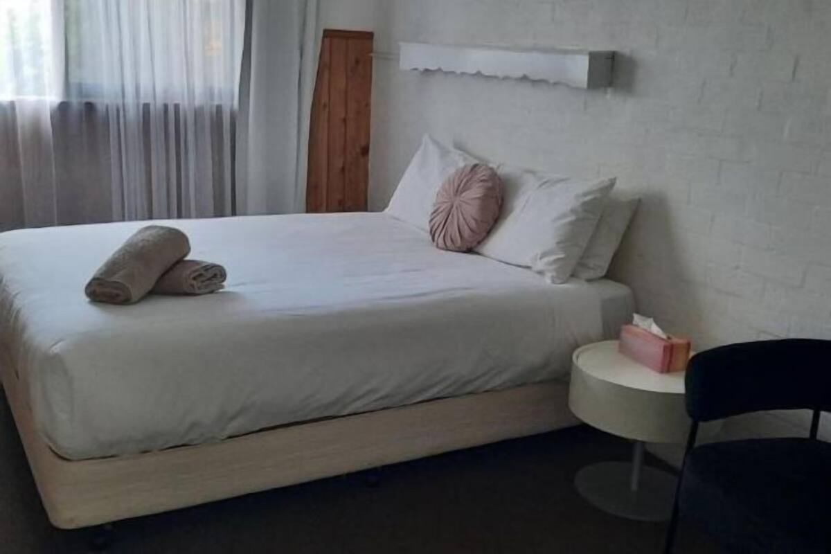 Escritorio, cortinas blackout y tabla de planchar con plancha