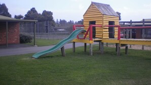 A playground with a slide and a wooden playhouse. - Best Western Colonial Village Motel (Warrnambool)