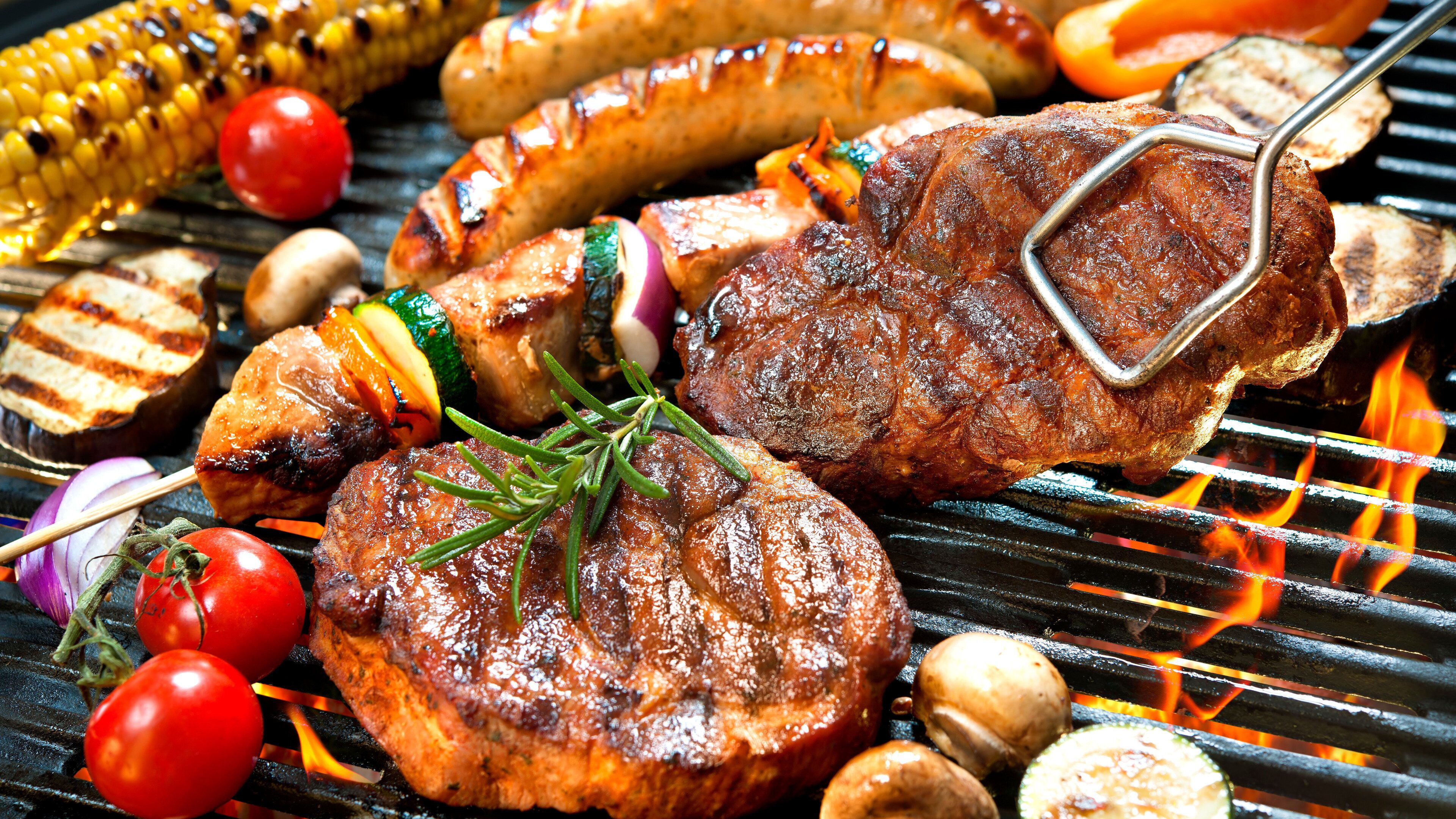A grill with various meats and vegetables being cooked.
