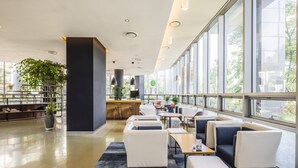 A spacious indoor area with seating arrangements, a reception desk, and large windows offering views of the outdoors. - Holiday Inn Incheon Songdo by IHG (Incheon)