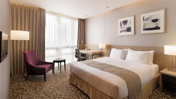 Une chambre d’hôtel avec un lit, un bureau, une chaise et une grande fenêtre avec des rideaux.