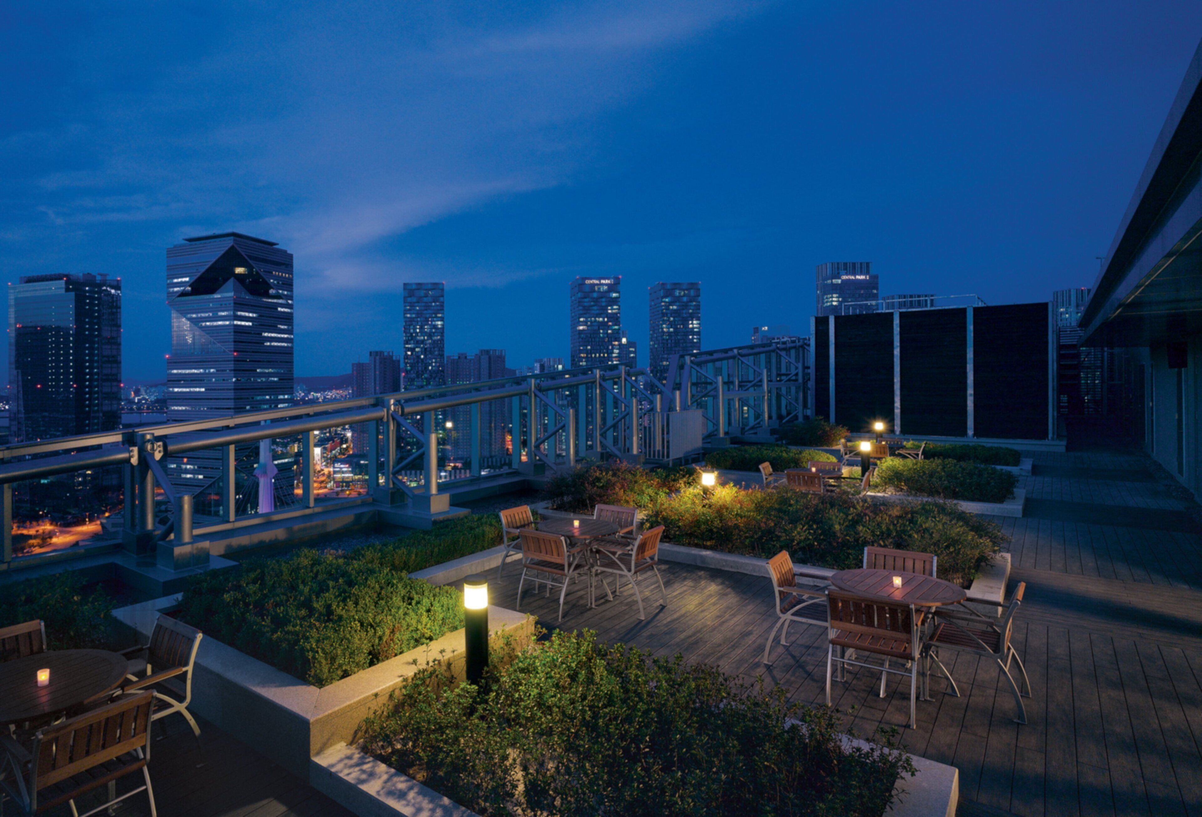 A rooftop terrace with outdoor seating and a city skyline view.