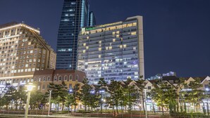A modern hotel with a glass facade, a Holiday Inn sign, and a classic building with arched windows. - Holiday Inn Incheon Songdo by IHG (Incheon)