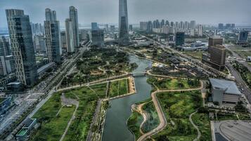 Un paisaje urbano con modernos rascacielos, un río con un puente y zonas verdes.