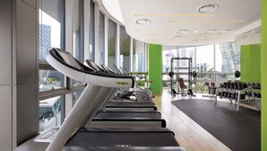 A gym with treadmills, weights, and a view of a cityscape through large windows. - Holiday Inn Incheon Songdo by IHG (Incheon)