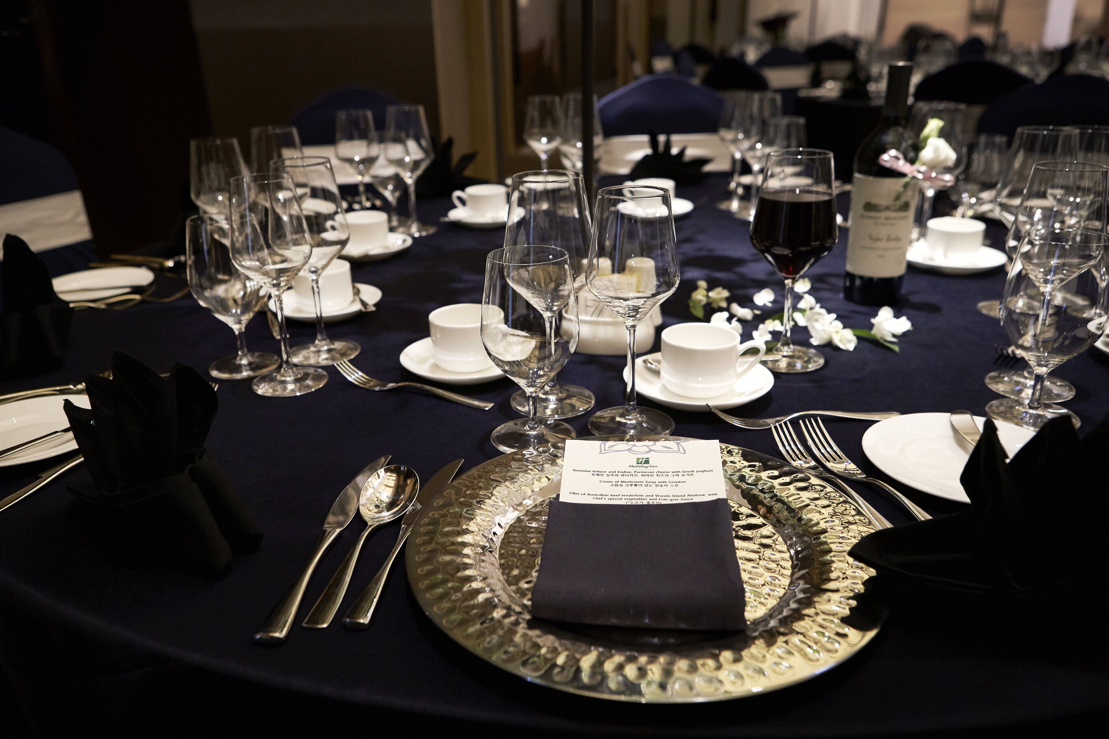 A formal dining table set with multiple wine glasses, plates, and cutlery.