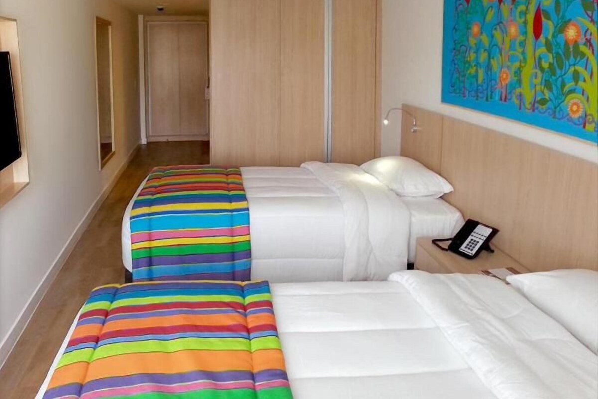 A hotel room with two beds, a telephone, and a painting on the wall.
