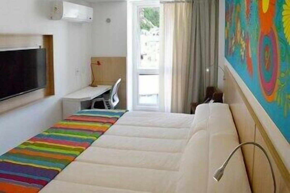A room with a bed, a desk, a chair, and a TV.