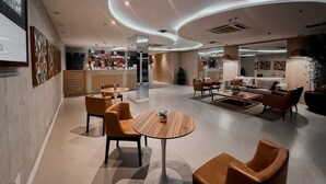 A modern interior with a reception desk, seating area, and a bar. - Royalty Rio Hotel (Rio de Janeiro)