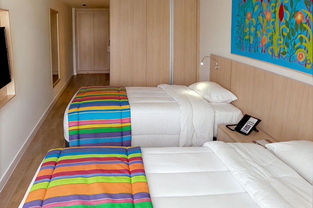 A hotel room with two beds, a telephone, and a painting on the wall.