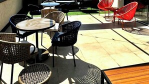 A rooftop terrace with outdoor seating, including wicker chairs and a table, under a glass roof with string lights. - Royalty Rio Hotel (Rio de Janeiro)