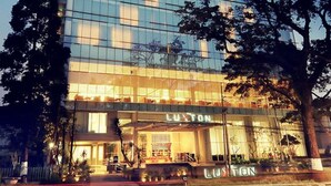 A modern hotel with a glass facade, named "LUXTON," featuring a prominent entrance and a well-lit lobby area. - The Luxton Bandung (Bandung)