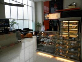 Un interior moderno con una vitrina de panadería, zona de estar y un amplio ventanal que proporciona luz natural.