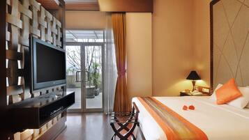 A hotel room with a bed, a TV, a desk, and a view of the outdoors.