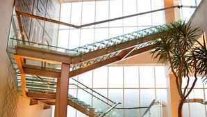 A modern interior with a glass staircase, a polished floor, and a large window providing natural light. - The Luxton Bandung (Bandung)