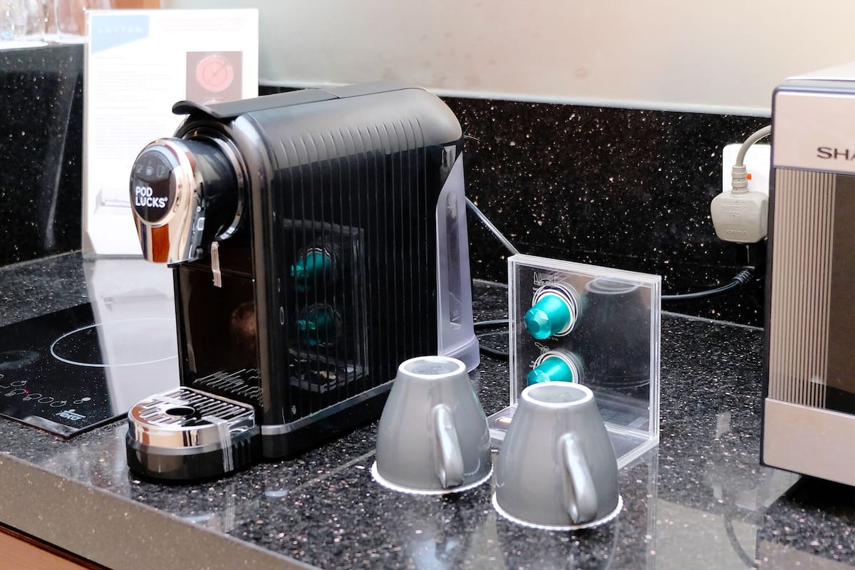 A coffee machine with a digital display, two cups, and a power outlet.