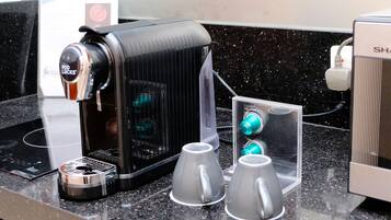 Eine Kaffeemaschine mit digitalem Display, zwei Tassen und einer Steckdose.