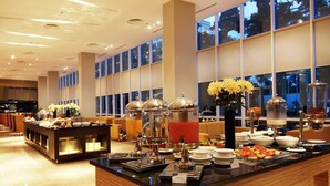 A buffet area with a variety of food items, including fruits and a hot beverage station. - The Luxton Bandung (Bandung)