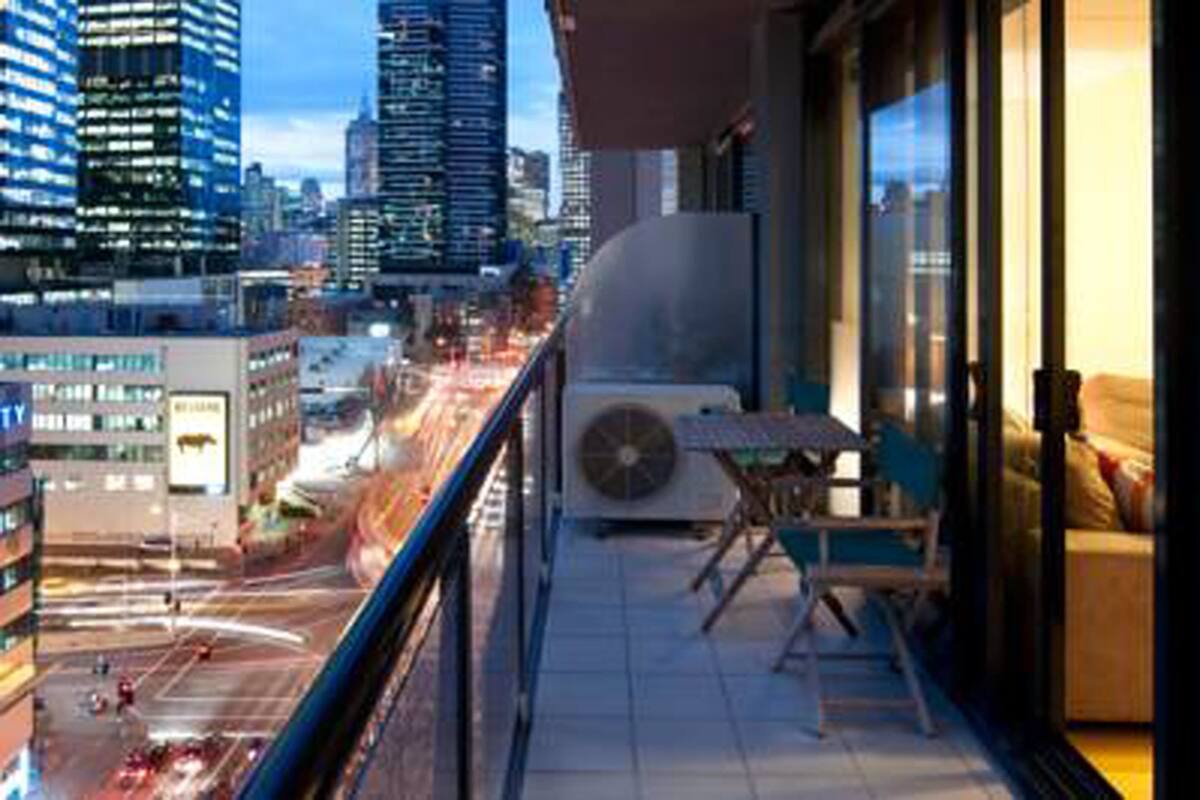 A balcony with a city view, a table, and a chair.