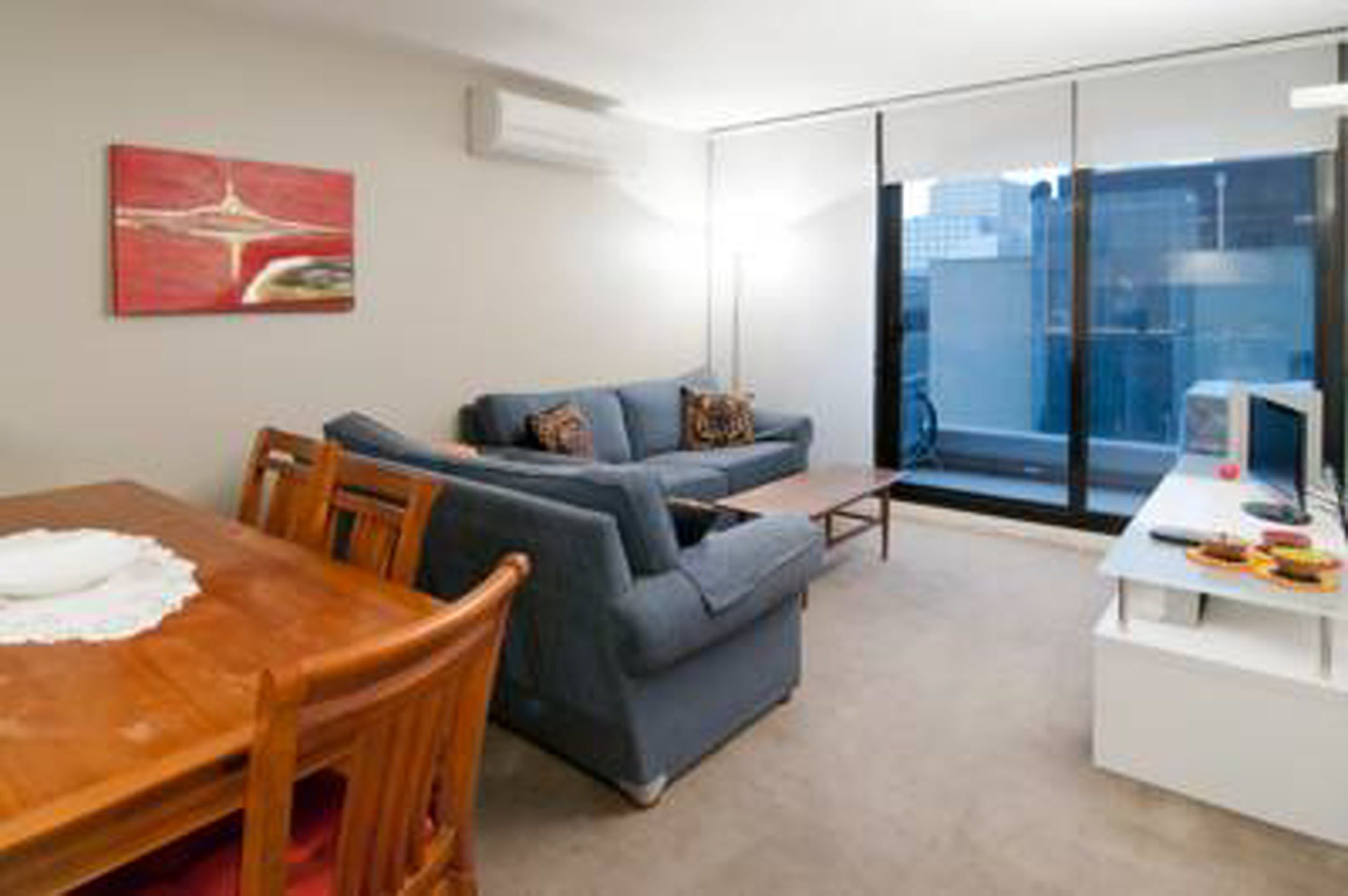 A modern living room with a sofa, a dining table with chairs, and a small white side table.