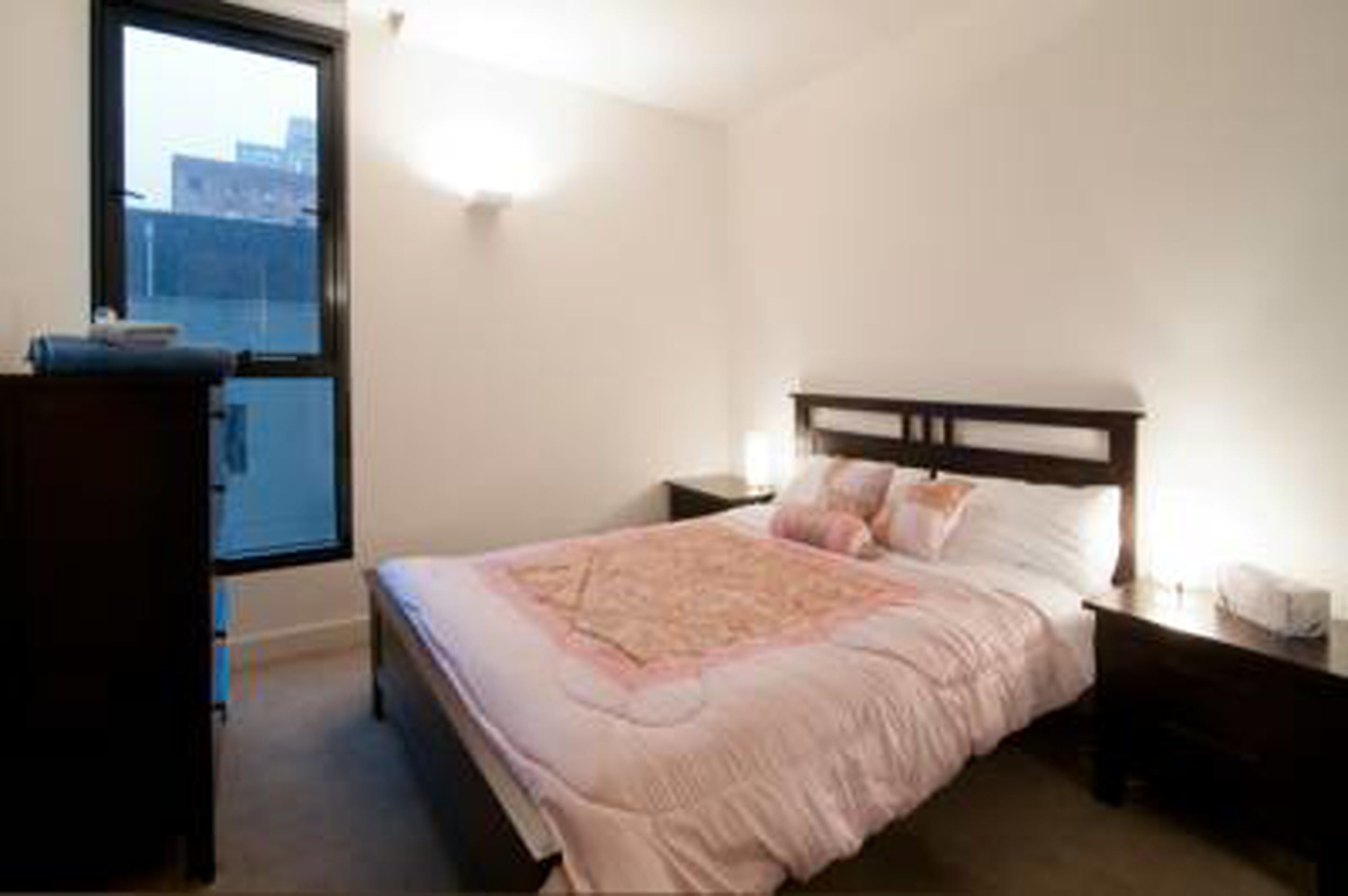 A bedroom with a bed, a dresser, a nightstand, and a window.