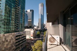 Un immeuble de grande hauteur avec une façade en verre, un parking et un ciel dégagé.