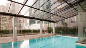 An indoor swimming pool with glass walls, surrounded by a modern urban setting. - Inner Melbourne Serviced Apartments (Southbank)