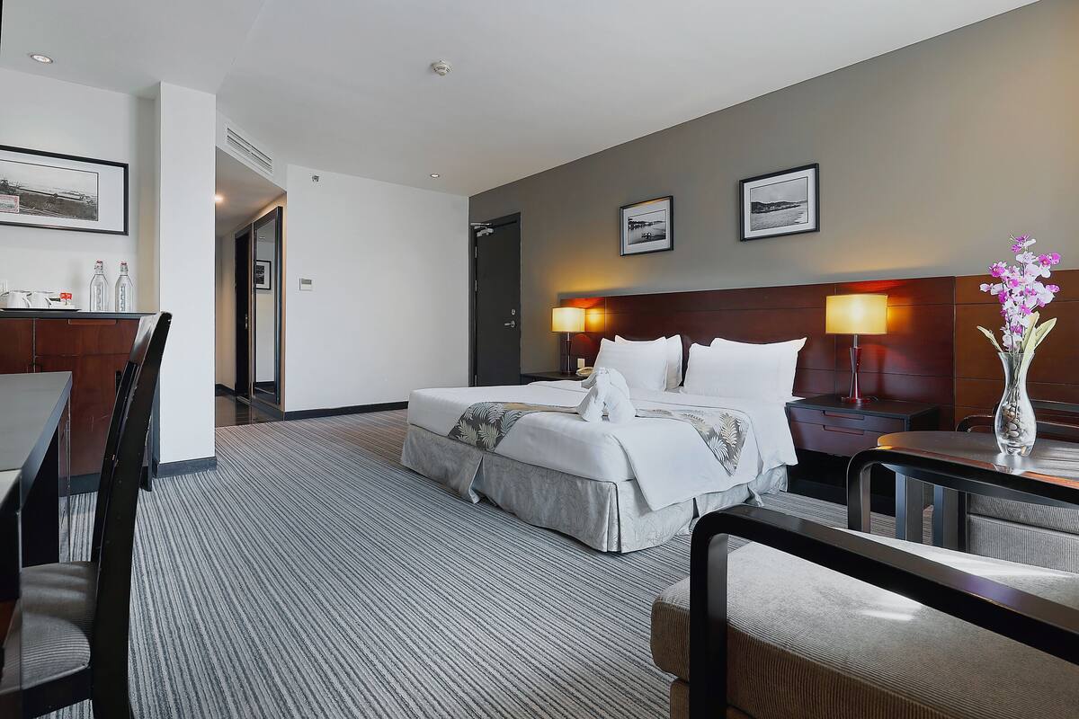 Una habitación de hotel con cama, mesitas de noche, escritorio y sillas.
