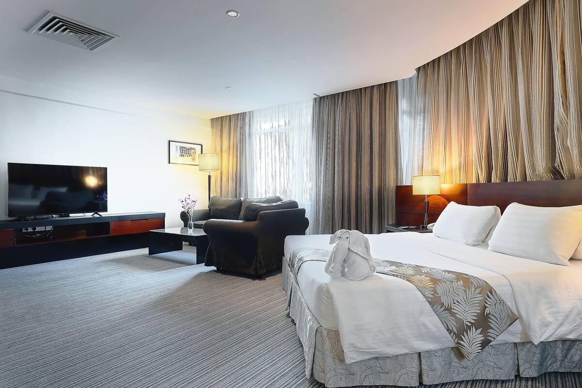 Una habitación de hotel con una cama grande, televisión, sofá y escritorio.