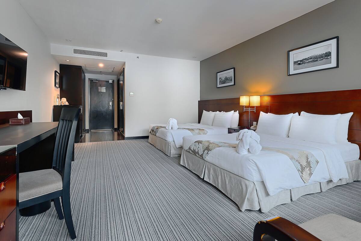 Una habitación de hotel con dos camas, un escritorio, una silla y un televisor.