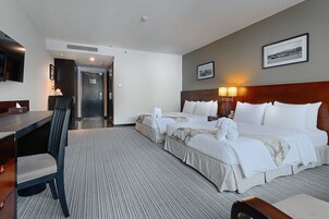 Una habitación de hotel con dos camas, un escritorio, una silla y un televisor.