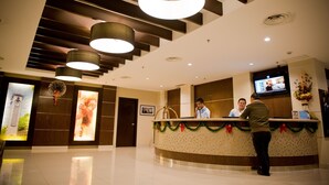 Zona de recepción de un hotel con un mostrador curvo, una pantalla de televisión y un diseño de techo moderno.