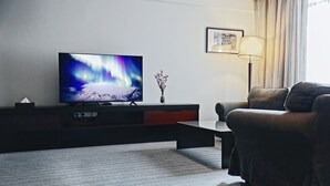 Una sala de estar moderna con una televisión de pantalla plana que muestra una escena de naturaleza, un sofá, una mesa de centro, una lámpara y un cuadro en la pared.