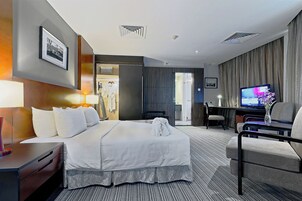 Une chambre d’hôtel avec un lit, un bureau, une télévision et une chaise.