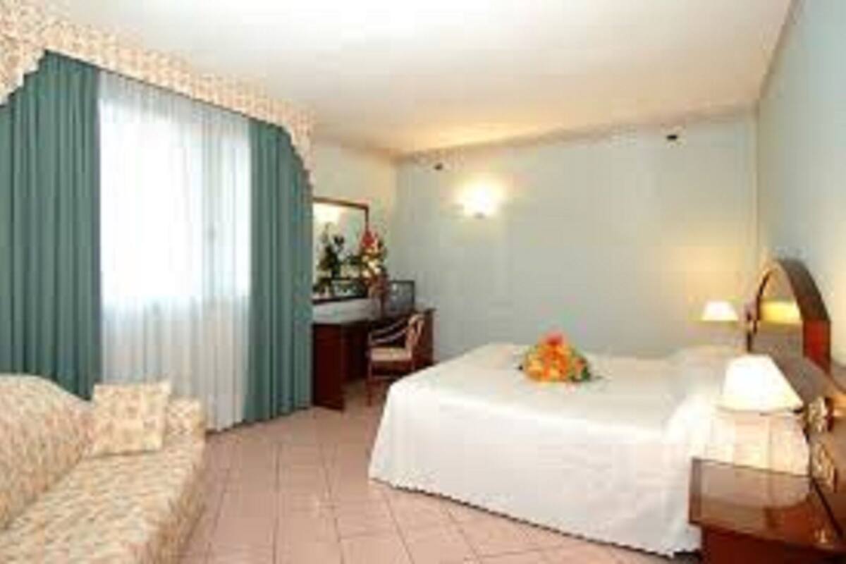 A hotel room with a bed, a desk, a chair, and a window with curtains.