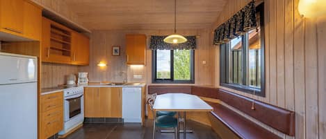 Eine Küche mit Holzausstattung, einem weißen Kühlschrank, einem Herd und einem Spülbecken.