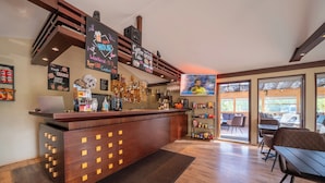 A bar area with a wooden counter, a chalkboard sign, and a television screen. - Minniborgir Cottages & Restaurant (Selfoss)