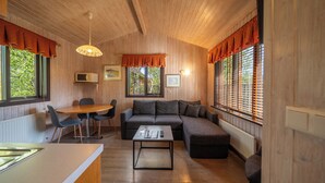 Een knus vertrek met een houten plafond, een hoekbank, een eettafel met stoelen en een salontafel.