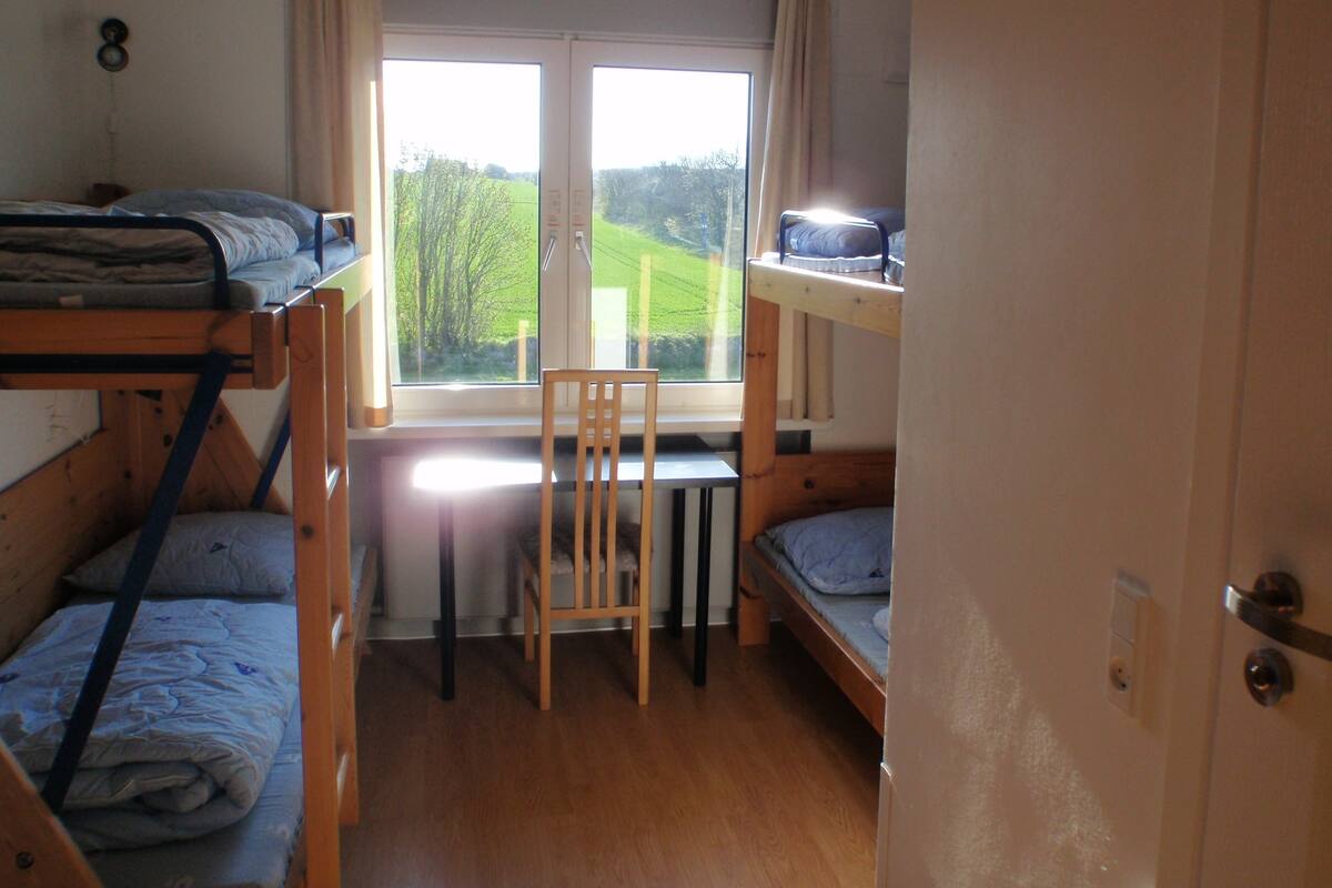A compact room with bunk beds, a window with curtains, and a chair.
