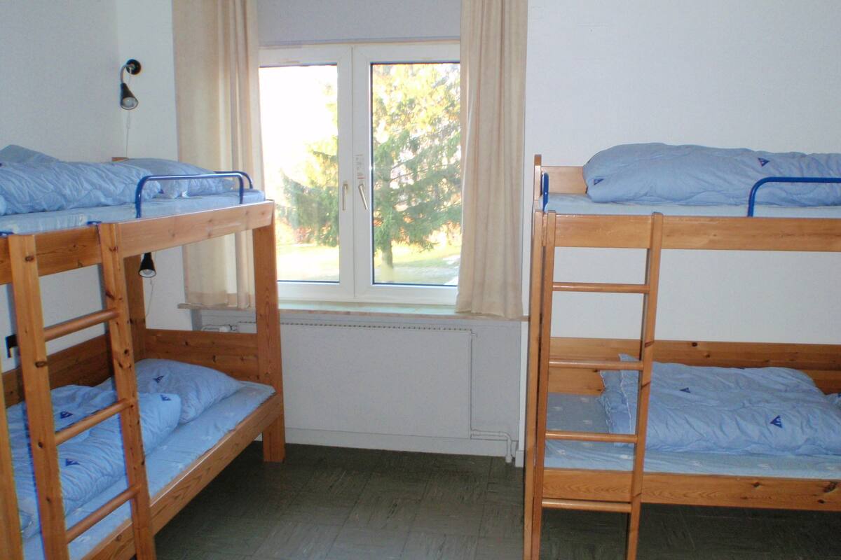 A room with two bunk beds, a window with curtains, and a radiator.