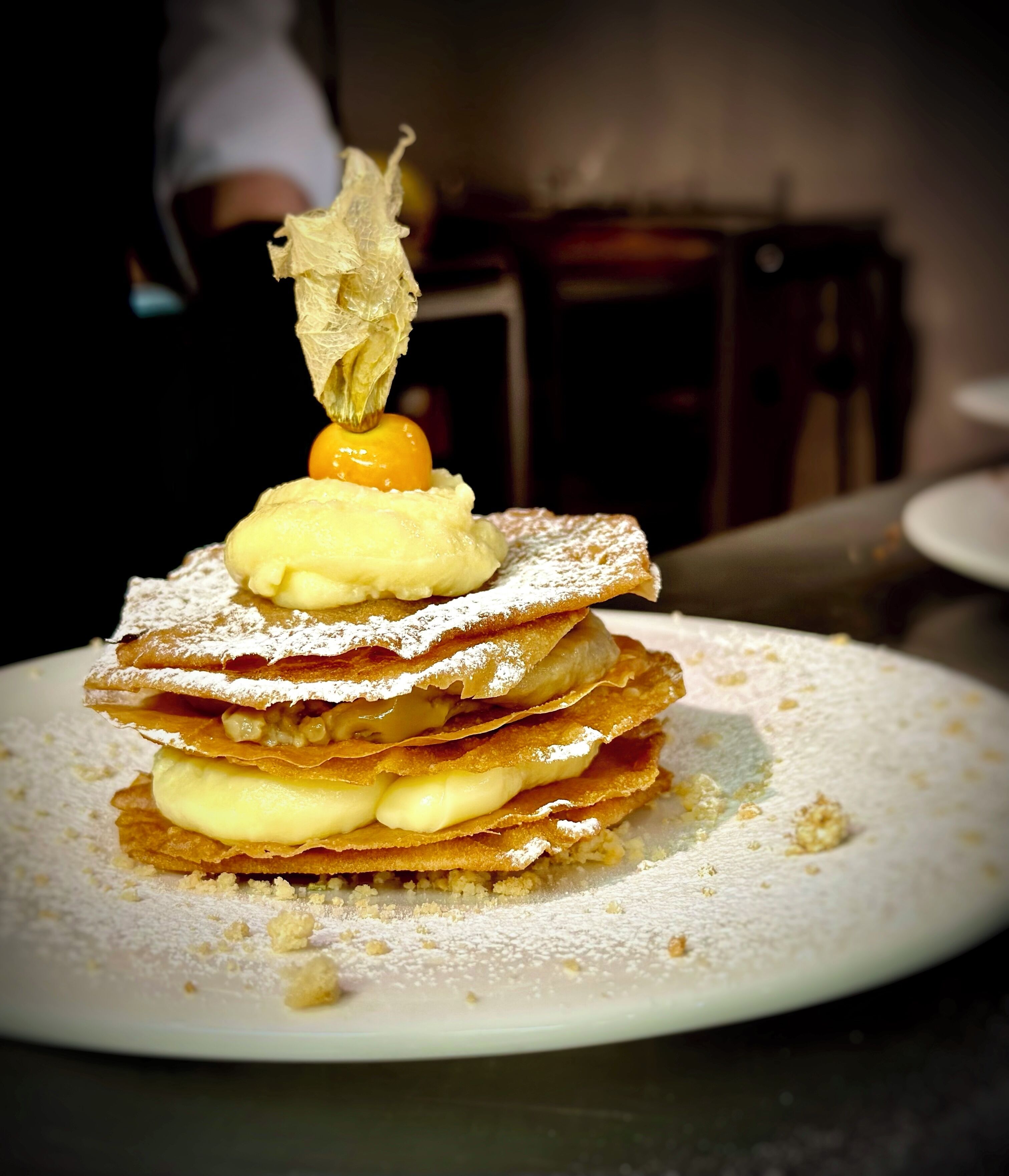 Un postre con varias capas de hojaldre y crema, espolvoreado con azúcar glas.