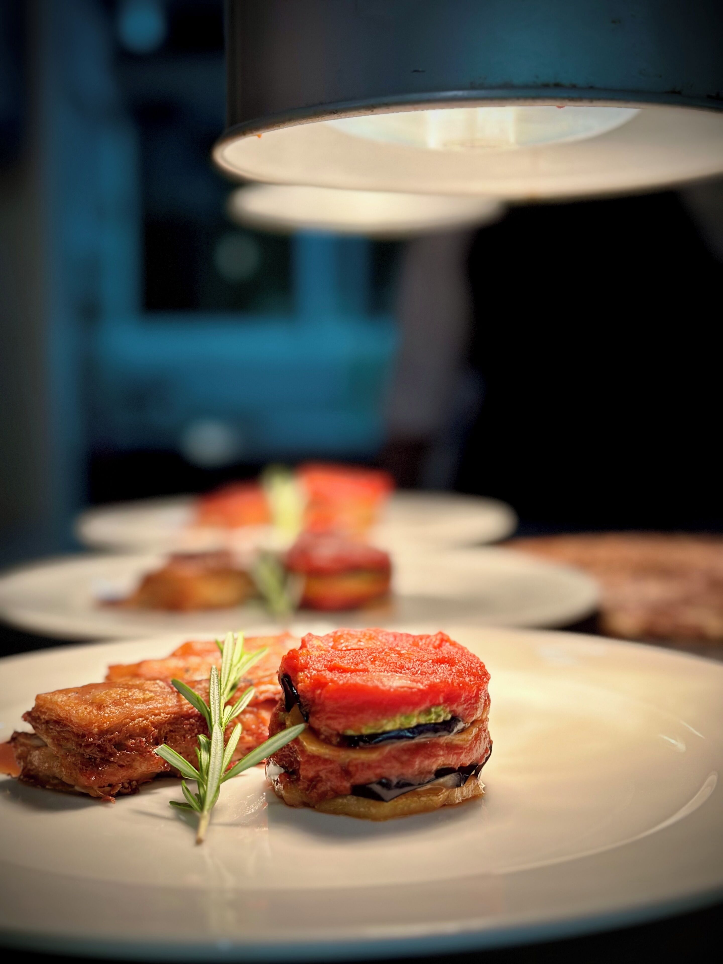 A close-up of a dish with a slice of meat and vegetables on a plate, with a blurred background.