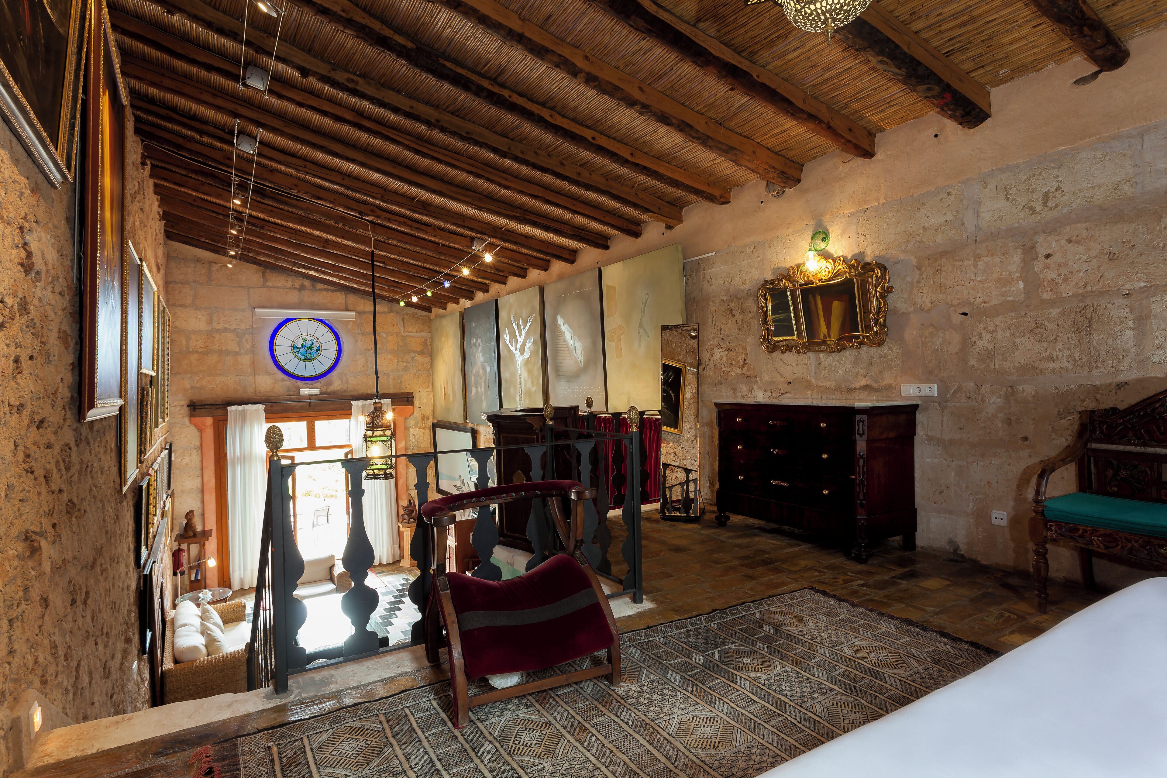 A room with a high ceiling, exposed beams, a fireplace, and a large window.