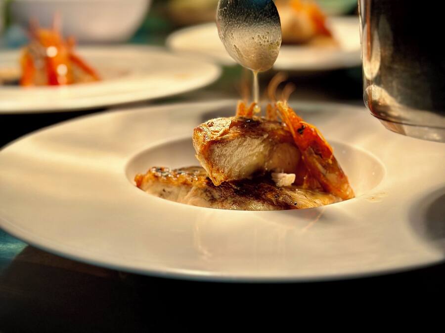 A person serving food on a white plate with a spoon.